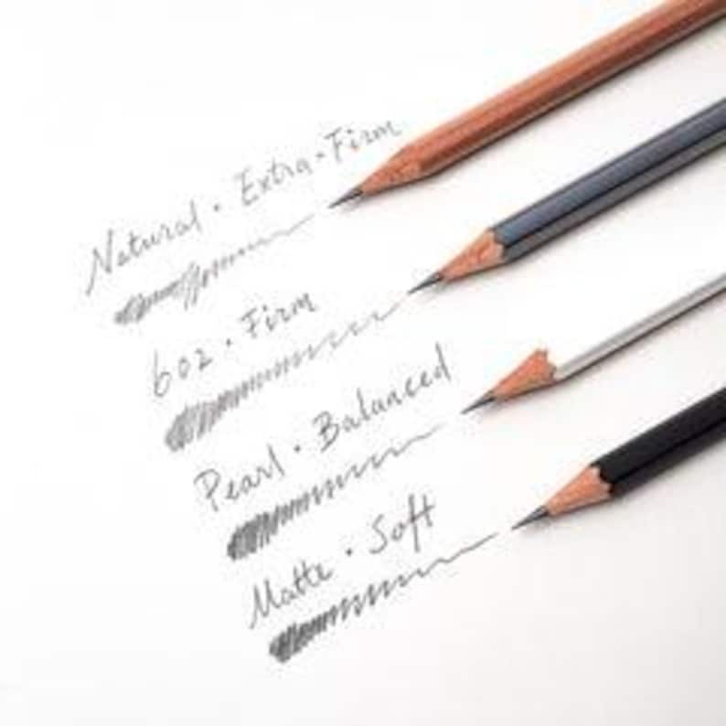 May include: Close-up of four pencils with different lead grades and labels. The pencils are labeled "Natural - Extra-Firm", "602 - Firm", "Pearl - Balanced", and "Matte - Soft".