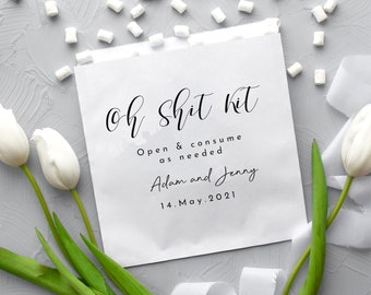 May include: White paper bag with black text that reads "Oh Shit Kit" and "Open & consume as needed". Below the text is "Adam and Jenny" and "14. May. 2021".
