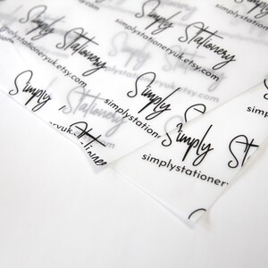 May include: Close-up of a stack of clear plastic sheets with the text "Simply Stationery" and the website address "simplystationeryuk.etsy.com" printed on them.