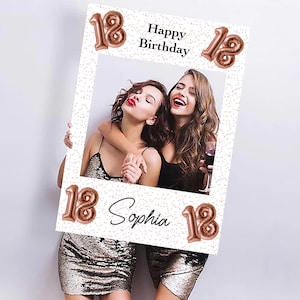Op de afbeelding: Een witte fotolijst met de tekst "Happy Birthday" en "Sophia" in zwart schrift. Het nummer "18" wordt herhaald in ros&eacute;gouden ballonlettertype. Twee vrouwen staan in de lijst, glimlachen en omarmen elkaar. De lijst heeft een stippenpatroon.