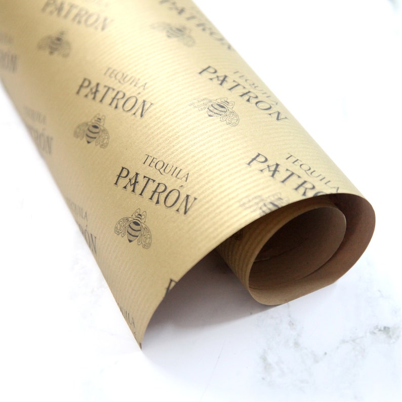 K&ouml;nnte beinhalten: Eine Rolle braunes Kraftpapier Geschenkpapier mit einem sich wiederholenden Muster aus schwarzen Bienen und dem aufgedruckten Text "Tequila Patron".