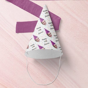 May include: White party hat with a repeating pattern of a person's face and the text "Happy 30th [Name]" in black. The hat has a purple and white polka dot pattern and a purple string.