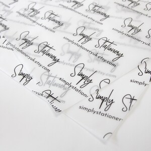 May include: Close-up of a stack of clear, translucent tissue paper with the text "Simply Stationery" repeated in black cursive writing. The text also includes the website address "simplystationeryuk.etsy.com".