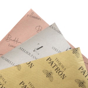 K&ouml;nnte beinhalten: Drei Bl&auml;tter braunes Papier mit verschiedenen Mustern und Texten. Das oberste Blatt ist rosa mit dem Text "0 y Comfort" und "Beddin" und "Luxu". Das mittlere Blatt ist beige mit dem Text "ZANGARE" und "ATELIER ZANG". Das unterste Blatt ist braun mit einem sich wiederholenden Muster von Bienen und dem Text "TEQUILA PATRON".