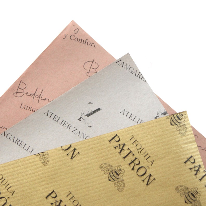 K&ouml;nnte beinhalten: Drei Bl&auml;tter braunes Papier mit verschiedenen Mustern und Texten. Das oberste Blatt ist rosa mit dem Text "0 y Comfort" und "Beddin" und "Luxu". Das mittlere Blatt ist beige mit dem Text "ZANGARE" und "ATELIER ZANG". Das unterste Blatt ist braun mit einem sich wiederholenden Muster von Bienen und dem Text "TEQUILA PATRON".