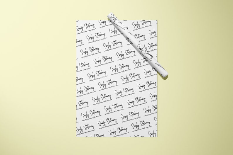 May include: White wrapping paper with a repeating pattern of the text "Simply Stationery" in black cursive writing. A white pen is rolled up on top of the paper.