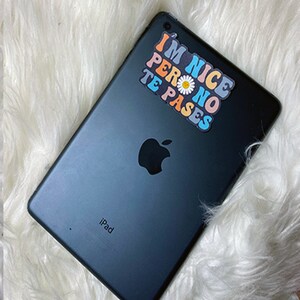 May include: A black iPad with a sticker that says "I'm Nice Pero No Te Pases" in rainbow colors with a white daisy in the middle.