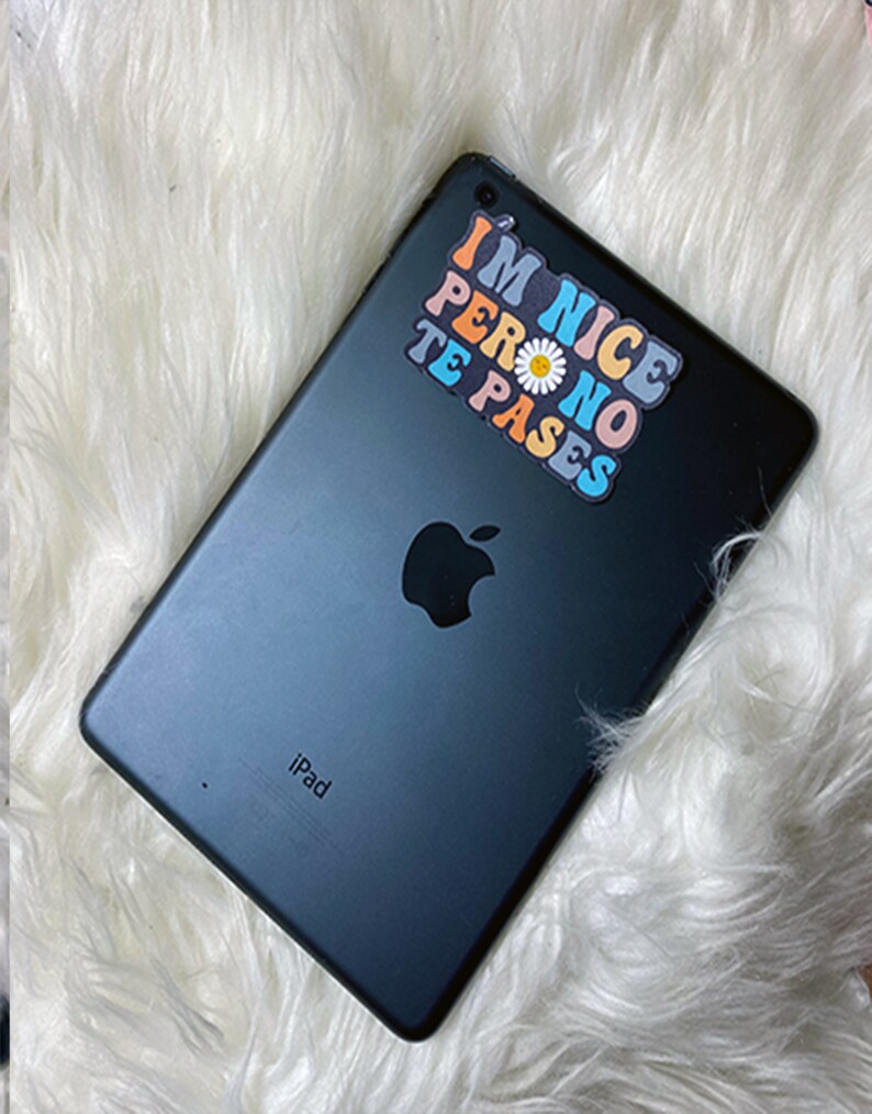 May include: A black iPad with a sticker that says "I'm Nice Pero No Te Pases" in rainbow colors with a white daisy in the middle.