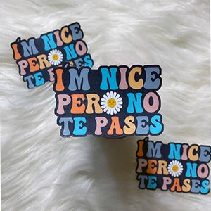 May include: Three colorful stickers with the text "I'm nice pero no te pases" in a retro font. The stickers feature a daisy with a smiley face.