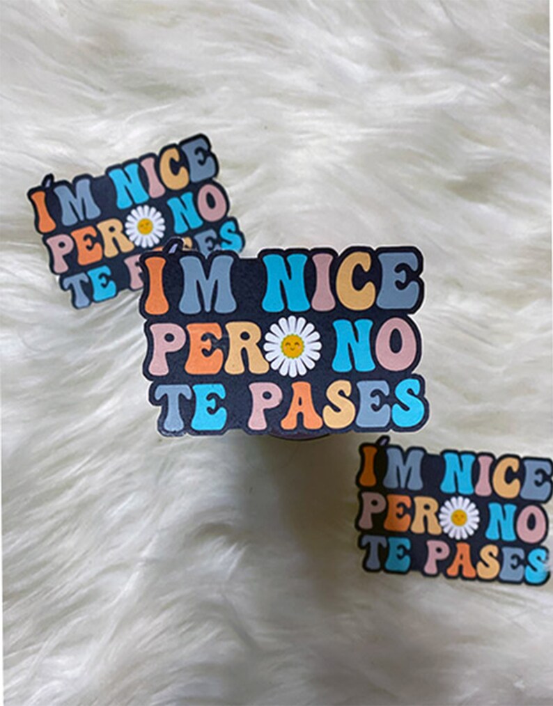 May include: Three colorful stickers with the text "I'm nice pero no te pases" in a retro font. The stickers feature a daisy with a smiley face.