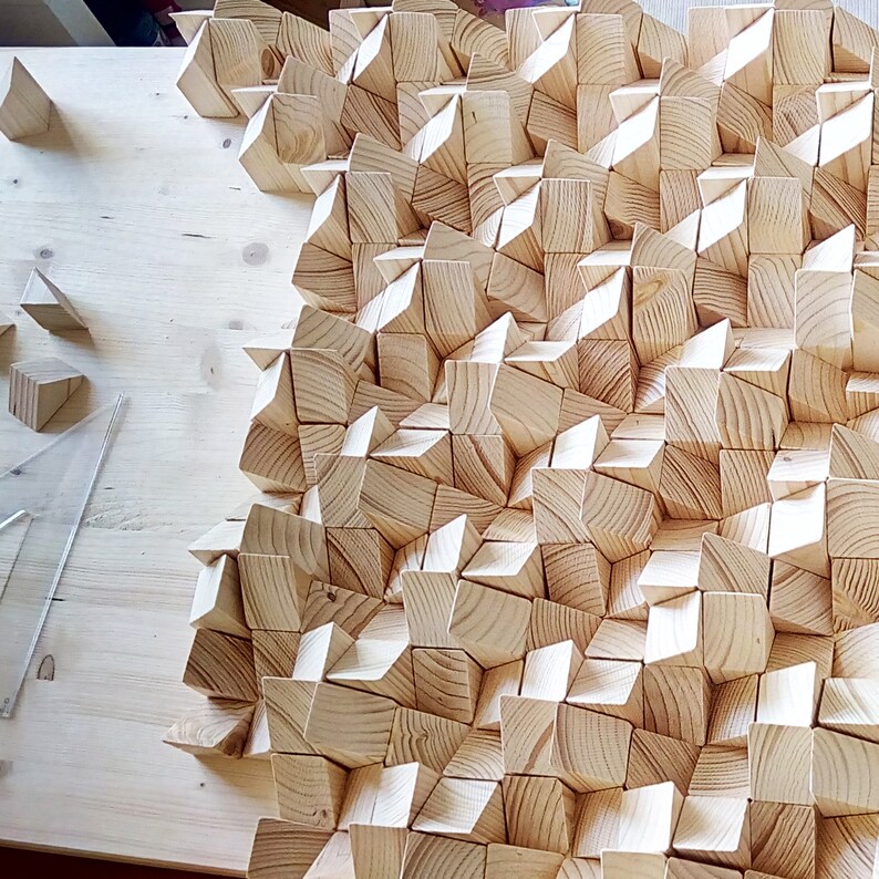May include: A wall panel made of many small, light brown wooden pieces arranged in a geometric pattern. The pieces are all different sizes and shapes, and they create a unique and interesting texture.