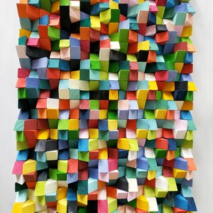 May include: A wall art piece made of colourful wooden blocks arranged in a geometric pattern. The blocks are in various shades of blue, green, red, yellow, and white.