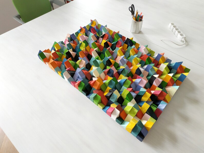 May include: A colourful geometric wall art piece made of wood. The piece is made up of many small, triangular shapes in a variety of colours, including red, orange, yellow, green, blue, and purple.