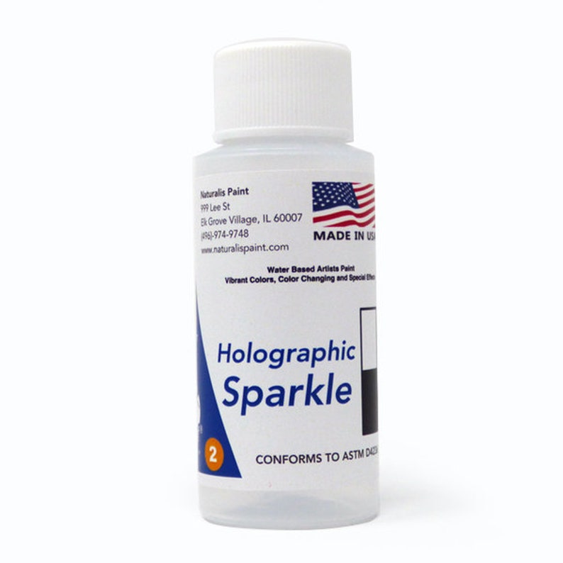 May include: A clear bottle of Holographic Sparkle water-based artist paint with a white cap. The label includes the text "Naturalis Paint" and "MADE IN USA". The bottle is approximately 4 inches tall.