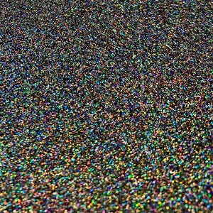 May include: Close-up of a surface covered in small, iridescent glitter particles. The glitter has a dark base color with a shimmering, rainbow effect. The overall appearance is textured and sparkling.