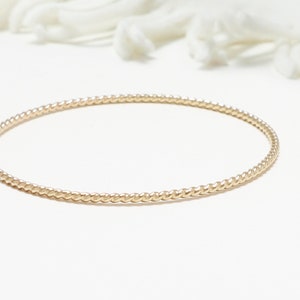 May include: A gold-toned bangle bracelet with a twisted rope design.