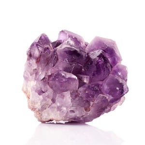 May include: A cluster of amethyst crystals, a purple gemstone, with a natural, rough texture. The crystals are arranged in a random, organic pattern, showcasing the beauty of the natural formation.