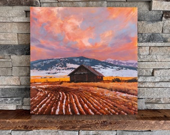 May include: A painting depicting a rustic wooden cabin situated in a field, with a snow-capped mountain range in the background. The sky is a vibrant orange and pink with clouds.