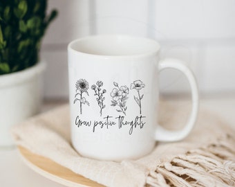 May include: White ceramic mug with a black line drawing of flowers and the text "Grow positive thoughts".