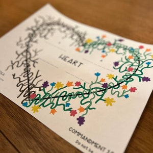 Puede incluir: Una tarjeta blanca con un dibujo de línea negra de un corazón con una vid y flores en forma de corazón. El texto "HEART" está impreso en negro en la parte superior de la tarjeta. El texto "COMMANDMENT 10" está impreso en negro en la parte inferior de la tarjeta.
