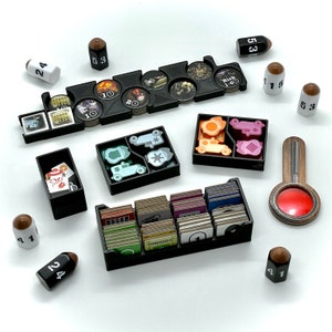 May include: A black organizer with multiple compartments for storing game pieces and cards. The organizer includes a compartment for dice, a compartment for cards, and a compartment for small game pieces. The organizer is made of plastic and has a black finish.