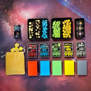 May include: A set of 10 small, colorful plastic storage boxes with lids. The boxes are filled with small, colorful plastic pieces. The boxes are arranged in two rows of five. The boxes are on a table with a starry pattern.