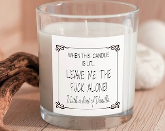 May include: A white candle in a clear glass jar with a label that reads "WHEN THIS CANDLE IS LIT... LEAVE ME THE FUCK ALONE! With a hint of Vanilla."