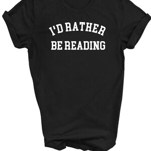 May include: Black t-shirt with white text that reads "I'd rather be reading" in a collegiate font.