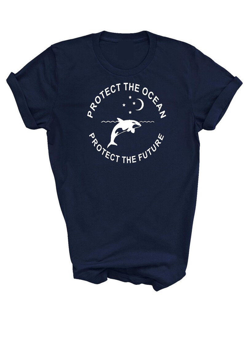May include: Navy blue t-shirt with a white graphic of a dolphin jumping out of the water with a crescent moon and stars above. The text "Protect the Ocean Protect the Future" is written in a circle around the dolphin.