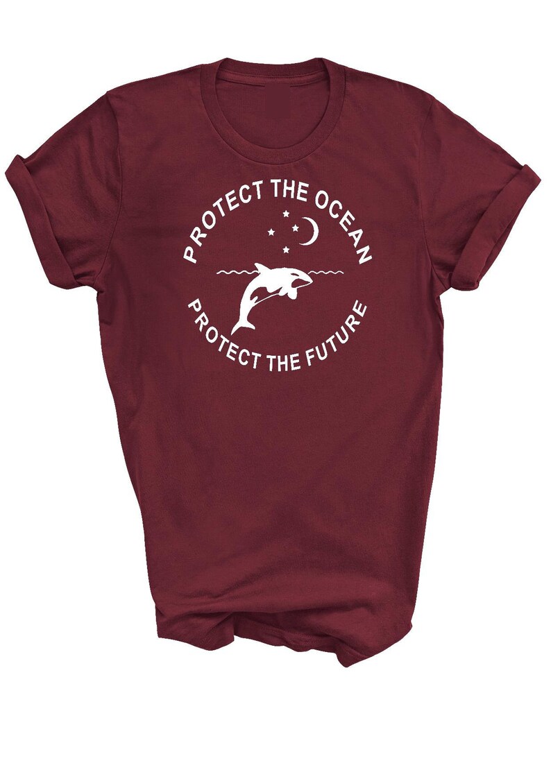 May include: A maroon t-shirt with a white circle graphic featuring a dolphin jumping out of the water with a crescent moon and stars above. The text "Protect the Ocean" is written around the top of the circle and "Protect the Future" is written around the bottom of the circle.