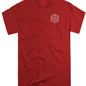 May include: A solid red short-sleeve t-shirt featuring a white line-art graphic of a twenty-sided die on the upper left chest area. The die graphic displays various numbers, with the number 20 prominently centered within the geometric shape.