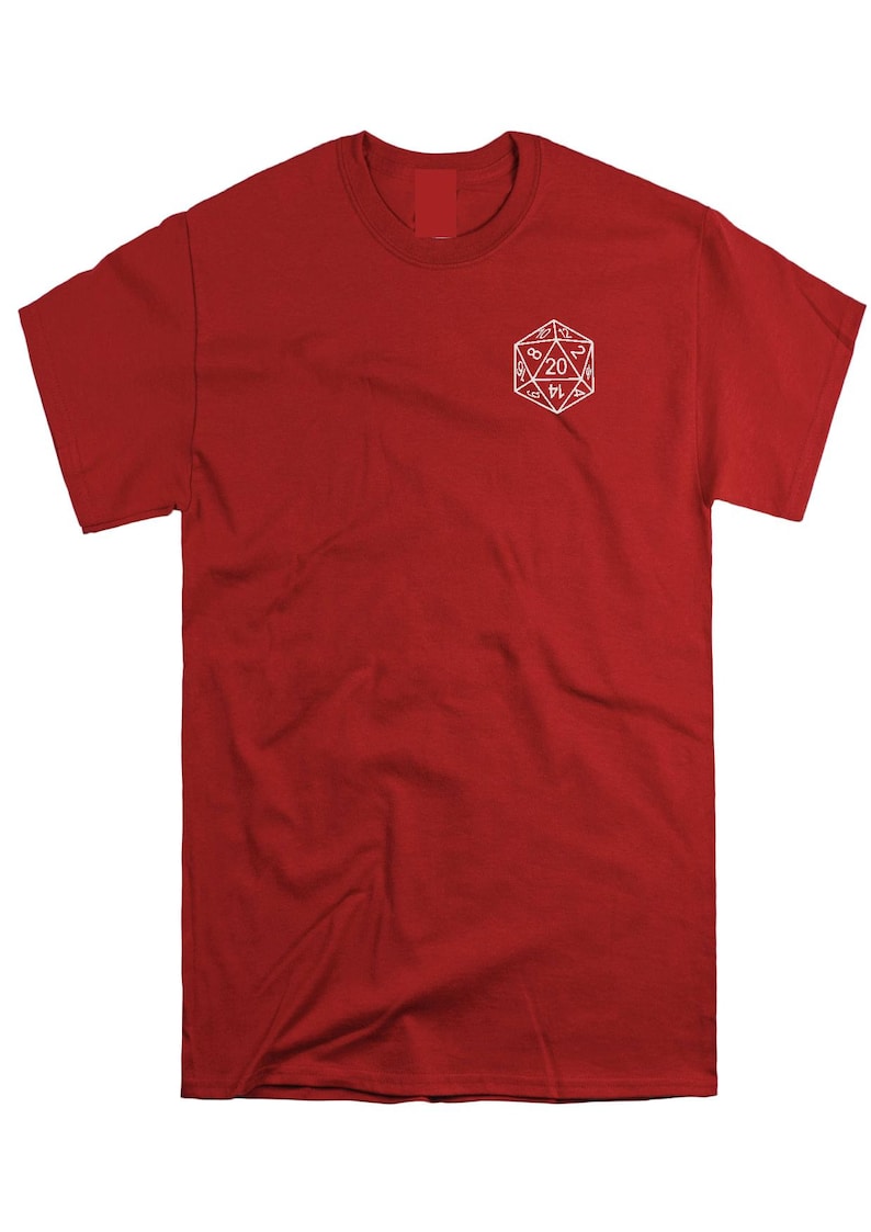 May include: A solid red short-sleeve t-shirt featuring a white line-art graphic of a twenty-sided die on the upper left chest area. The die graphic displays various numbers, with the number 20 prominently centered within the geometric shape.