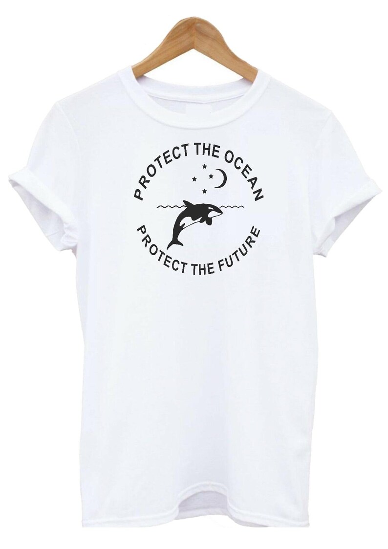 May include: White t-shirt with a black graphic design featuring an orca jumping out of the water with a crescent moon and stars above. The text reads "Protect the Ocean, Protect the Future."