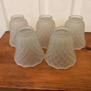 May include: A set of five bell-shaped glass light shades with a frosted finish. Each shade features a raised lattice pattern with vertical lines along the upper section and a scalloped bottom edge, designed for standard light fixture installation.
