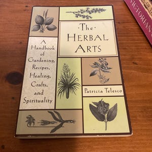 May include: A rectangular book titled The Herbal Arts by Patricia Telesco. The cover features a grid layout with light green and tan panels, each displaying black and white botanical illustrations of various plants, herbs, and flowers.
