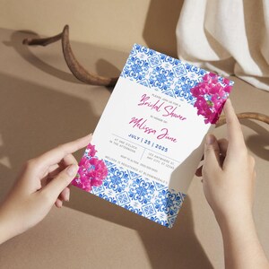 Puede incluir: Una invitación de ducha nupcial con estampado azul y blanco con flores rosas. La invitación dice "Por favor, únase a nosotros para una ducha nupcial en honor a Melissa June" y "Julio 25, 2025".