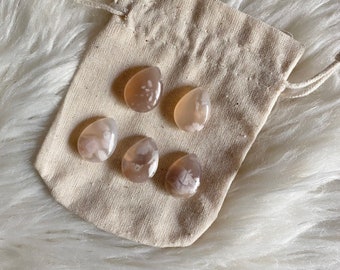 May include: Five white and brown agate stones in a small white drawstring bag. The stones are smooth and have a natural, organic look.