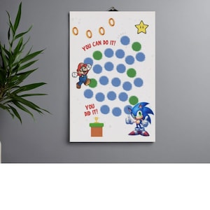 May include: A white reward chart featuring Mario and Sonic the Hedgehog. The chart includes the text YOU CAN DO IT! and YOU DID IT!, gold rings, a yellow star, a green pipe with a trophy, and a grid of blue and green circles for tracking.
