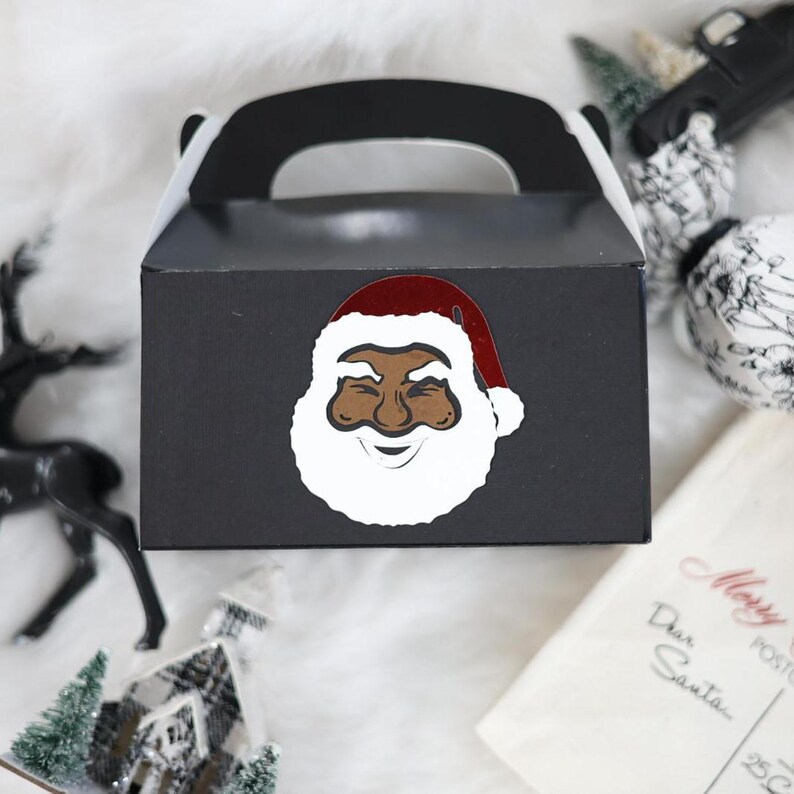 May include: Black and white Santa Claus face with a red hat on a black favour box with a handle. The box is decorated with a white border.