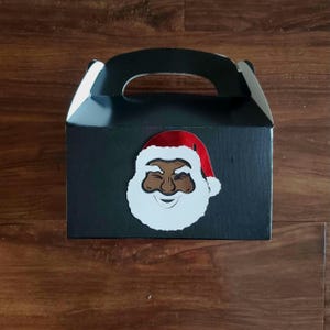 May include: Black gift box with a handle, decorated with a white and red Santa Claus face.
