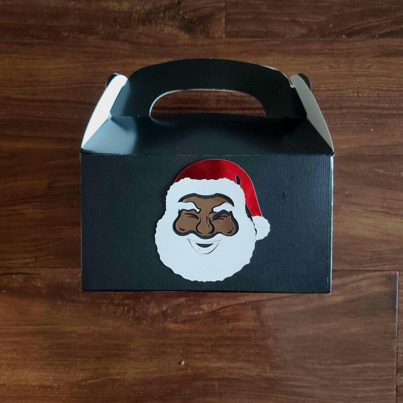 May include: Black gift box with a handle, decorated with a white and red Santa Claus face.