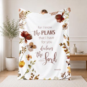May include: A white throw blanket featuring a floral border in shades of brown, orange, and yellow. The center text reads: for I know the PLANS that I have for you declares the Lord Jeremiah 29:11, with the name Amanda printed at the bottom.