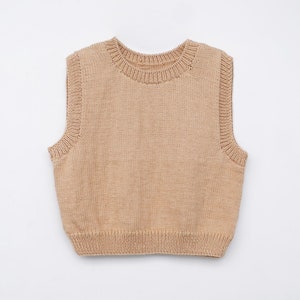 Op de afbeelding: Een gebreid vest zonder mouwen in een lichtbruine kleur. Het vest heeft een ronde halslijn en een geribbelde textuur.