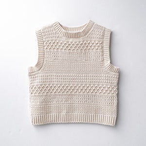 May include: A cream-coloured crocheted sleeveless vest with a textured pattern.