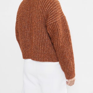 May include: A brown turtleneck sweater with a chunky knit texture.