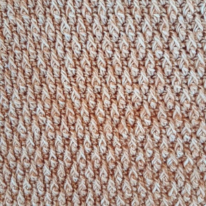 May include: Close-up of a brown and white crocheted fabric with a textured, diagonal pattern.