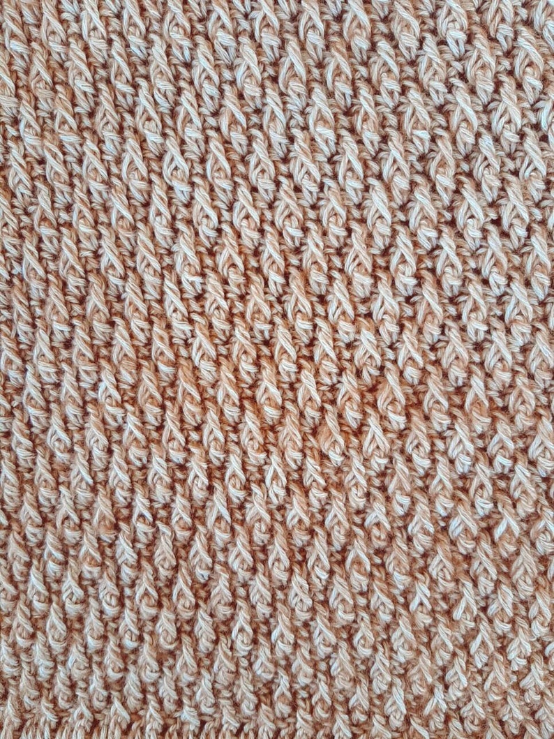 May include: Close-up of a brown and white crocheted fabric with a textured, diagonal pattern.