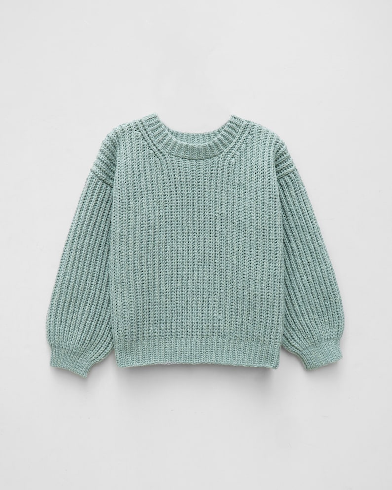 May include: A light sage green long-sleeve sweater featuring a chunky ribbed knit texture, a rounded crew neckline, and dropped shoulder seams. The garment has a thick ribbed hem at the waist and cuffs, providing a structured silhouette.