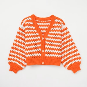 May include: Orange and white striped crochet cardigan with a button fastening.