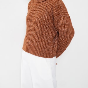 May include: A brown turtleneck sweater with a chunky knit texture.